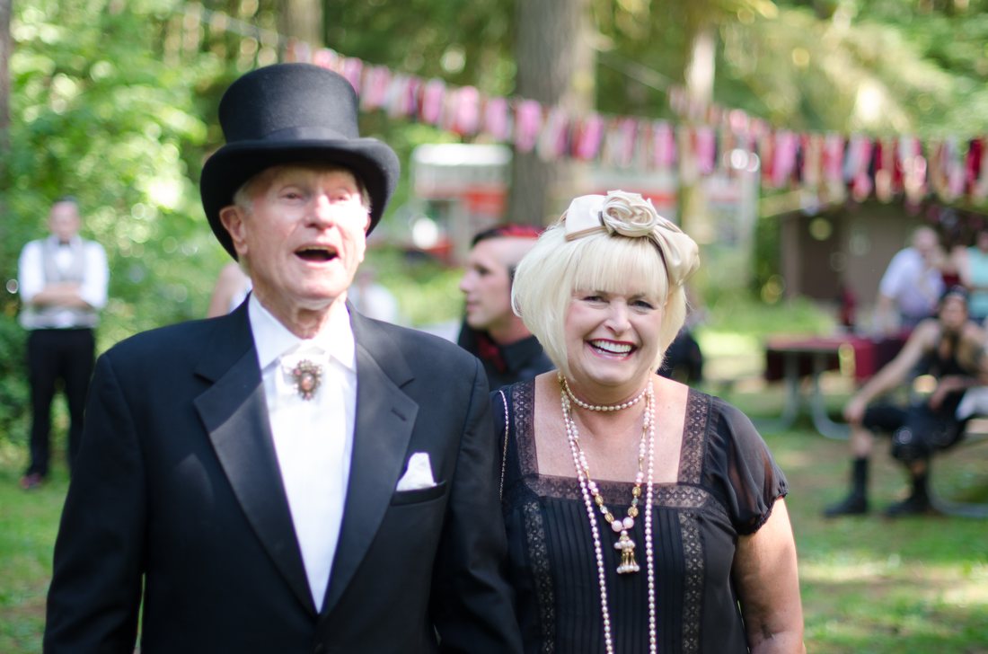 Older couple in top hat and tails laughing together at the reception