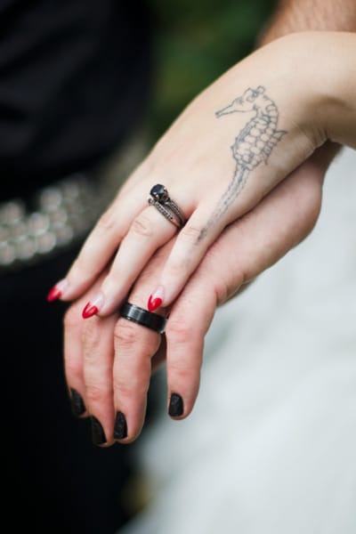 Close-up of couple's hands with black wedding bands and seahorse tattoo - Portland wedding